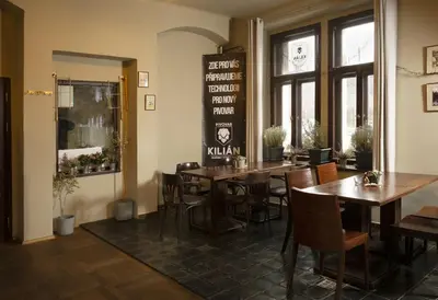 a restaurant with wooden tables and chairs in a room at Hotelové Pokoje Kolčavka in Prague