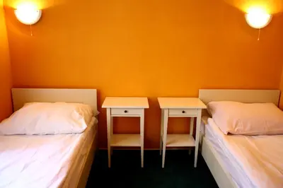 two twin beds in a room with orange walls at Hotelové Pokoje Kolčavka in Prague