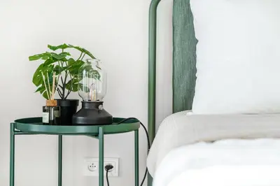 a green table with a plant on it next to a bed at Rentero One bedroom O2 Arena Dinopark Apartment in Prague