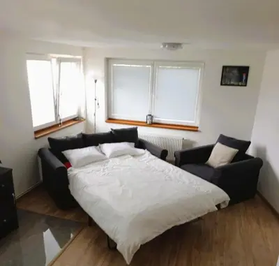 a living room with a table and chairs and a clock at Bnest in Beroun