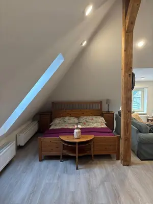 a bedroom with a bed and a wooden table at Malebný byt pod hradem Křivoklát in Křivoklát