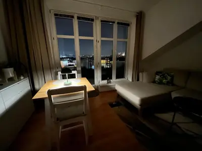 a living room with a table and a couch and a window at Cozy Studio with Prague panorama view in Prague