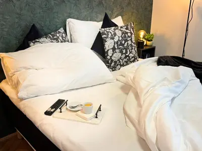 a bed with a tray with a remote control on it at Cinematic Apartment with Pool Table & Cinema room in the heart of Prague in Prague