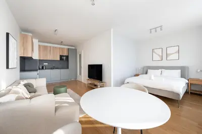 a white living room with a couch and a table at Fresh All-in Apartment Prague in Prague