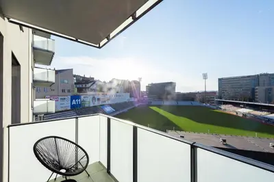 a chair on a balcony with a baseball field at Fresh All-in Apartment Prague in Prague
