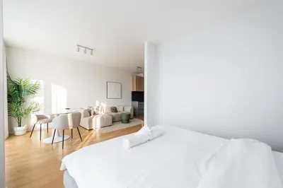 a white bedroom with a white bed and a dining room at Fresh All-in Apartment Prague in Prague