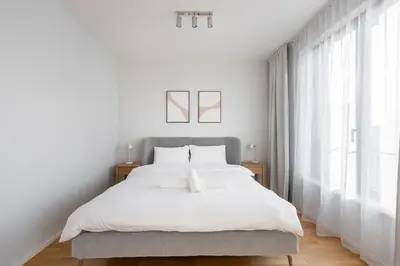 a white bedroom with a large bed and windows at Fresh All-in Apartment Prague in Prague