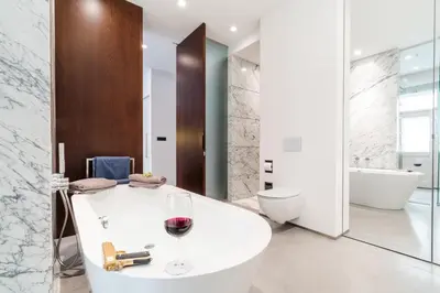 a bathroom with a white tub and a glass of wine at The Grand Krocínova Loft - Golden Bond Retreat in Prague