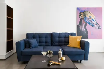 a blue couch in a living room with a painting of a horse at The Grand Krocínova Loft - Golden Bond Retreat in Prague