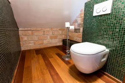 a bathroom with a toilet and a green tiled wall at Pension U Hastrmana in Prague
