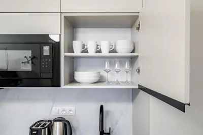 a kitchen with a microwave and wine glasses on shelves at Blueground Prague 2 furnished Náměstí Míru PRG-44 in Prague