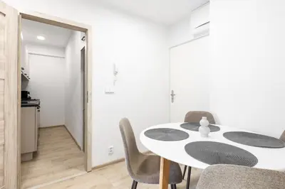 a white dining room with a white table and chairs at 2 bedroom apartment with a terrace near the metro in Prague