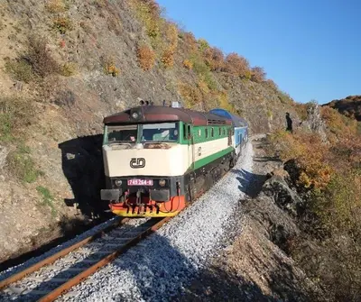 a green and white train traveling down the tracks at Domeček Pikovice in Píkovice