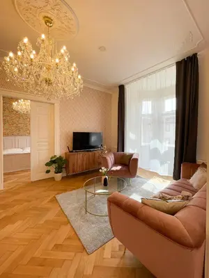 a living room with a couch and a chandelier at Stupartska Grand Residence in Prague