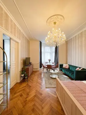 a living room with a green couch and a chandelier at Stupartska Grand Residence in Prague