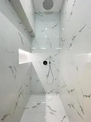 a white bathroom with white marble walls and a shower at Stupartska Grand Residence in Prague