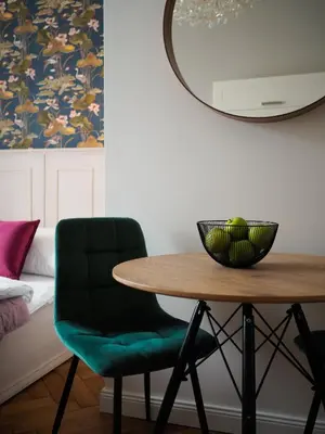 a dining room table with a green chair and a mirror at Stupartska Grand Residence in Prague