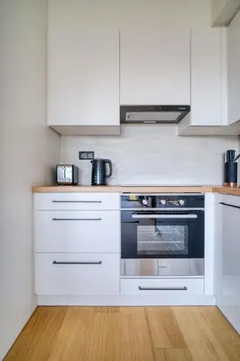 a kitchen with white cabinets and a black oven at Czech TESLA apartment by Rentez in Prague