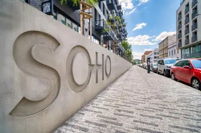 a street with cars parked next to a wall with the word schizophrenia at Czech TESLA apartment by Rentez in Prague