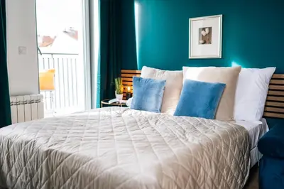 a bedroom with a large white bed with blue walls at WagnerStays Modern Suites Residence in Prague