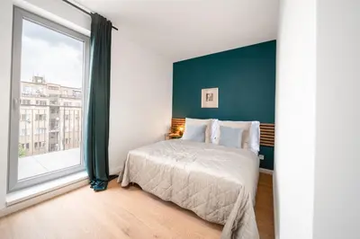 a bedroom with a bed and a large window at WagnerStays Modern Suites Residence in Prague