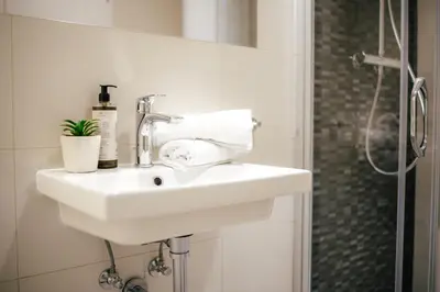 a white sink in a bathroom with a shower at WagnerStays Modern Suites Residence in Prague