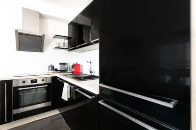 a kitchen with black cabinets and a sink and a stove at The Loft Holešovice in Prague
