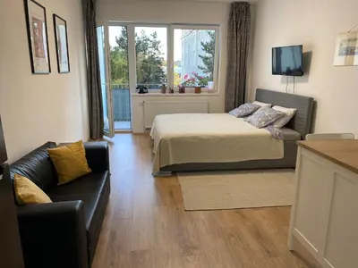 a bedroom with a bed and a couch and a window at NEW apartment in Prague in Prague