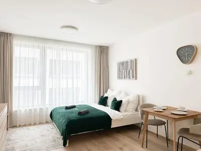 a white bedroom with a bed and a table at REAL Living by REFA Karlin 406 in Prague