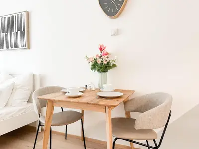 a wooden table with chairs and a vase with flowers at REAL Living by REFA Karlin 406 in Prague