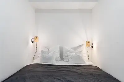 a white bedroom with a bed with white pillows at REAL Living by REFA Karlin 305 in Prague