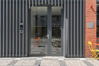 an open glass door of a building with chairs inside at REAL Living by REFA Karlin 305 in Prague