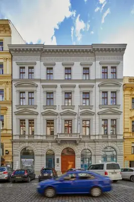 a blue car driving in front of a large building at Modern & Elegant, 3 min of Wenceslas Square in Prague