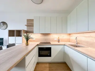 a kitchen with white cabinets and a wooden counter top at REAL Living by REFA Balcony Retreat 91 in Prague