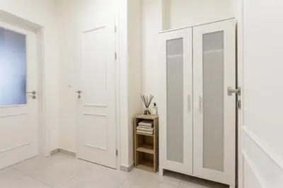 a white hallway with white doors and a shelf at Chic Flat on Jecna Walk to Wenceslas Sq and Museum in Prague