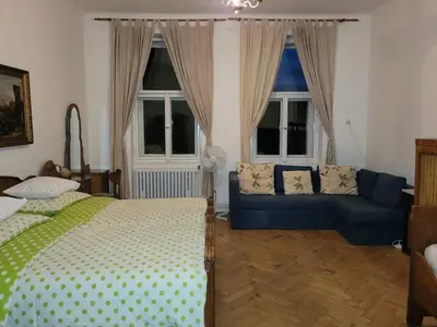 a bedroom with a bed and a couch and windows at Bright 2BDR sleeps 8 near center M1 in Prague