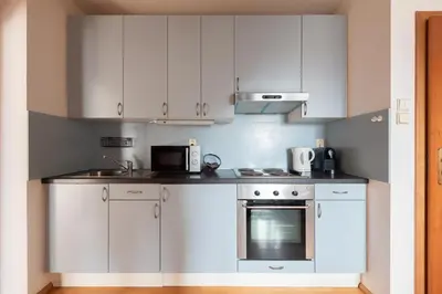 a white kitchen with white cabinets and a microwave at Morya Sky Apartment in Prague