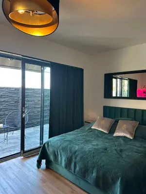 a bedroom with a green bed and a balcony at TAVI Apart-Hotel in Nupaky
