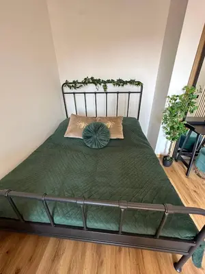 a bedroom with a bed with a green comforter at TAVI Apart-Hotel in Nupaky