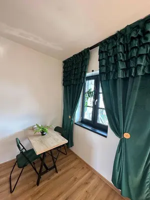 a room with a table and a window with green curtains at TAVI Apart-Hotel in Nupaky