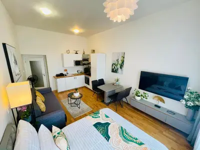 a living room with a couch and a tv and a table at Prague 1 Center Modern 2BR Apartment with Panoramic Museum View and King Bed in Prague
