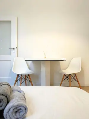 a bedroom with a bed and two white chairs at Small City Apartment in Prague