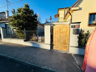 a house with a wooden gate with a dog in it at Apartmán v klidné části Benešova in Benešov