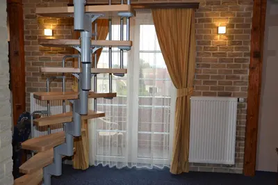 a wooden spiral book shelf in front of a window at Penzion Aurooms in Zlatníky