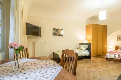 a room with two beds and a table with flowers on it at Karmelitska 1 luxury 1 bedroom in Prague