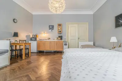a bedroom with a white bed and a kitchen with a table at Karmelitska 2 luxury 1B apartment in Prague