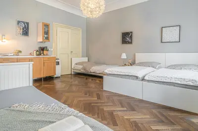 a bedroom with three beds and a kitchen with a chandelier at Karmelitska 2 luxury 1B apartment in Prague