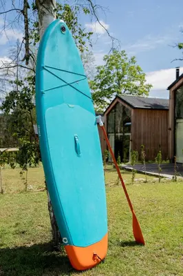 a blue and orange surfboard sitting on the grass at Moderní chata se zastřešenou terasou v docházkové vzdálenosti na pláž in Nalžovické Podhájí