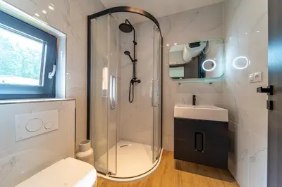 a bathroom with a shower and a toilet and a sink at Moderní chata se zastřešenou terasou v docházkové vzdálenosti na pláž in Nalžovické Podhájí