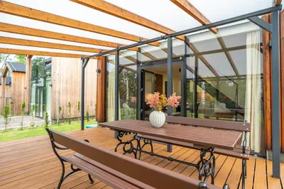 a glass house with a picnic table on a deck at Moderní chata se zastřešenou terasou v docházkové vzdálenosti na pláž in Nalžovické Podhájí